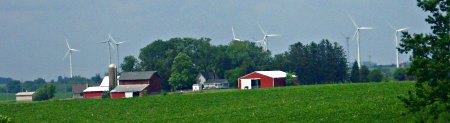 Windmills peek above farm buildings west of Interstate 35, near Paw Paw, Illinois